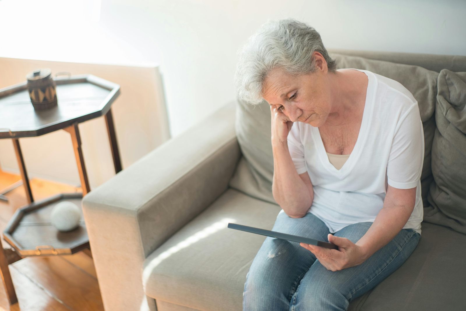 An older woman sitting on a couch and looking at a portrait | Source: Pexels