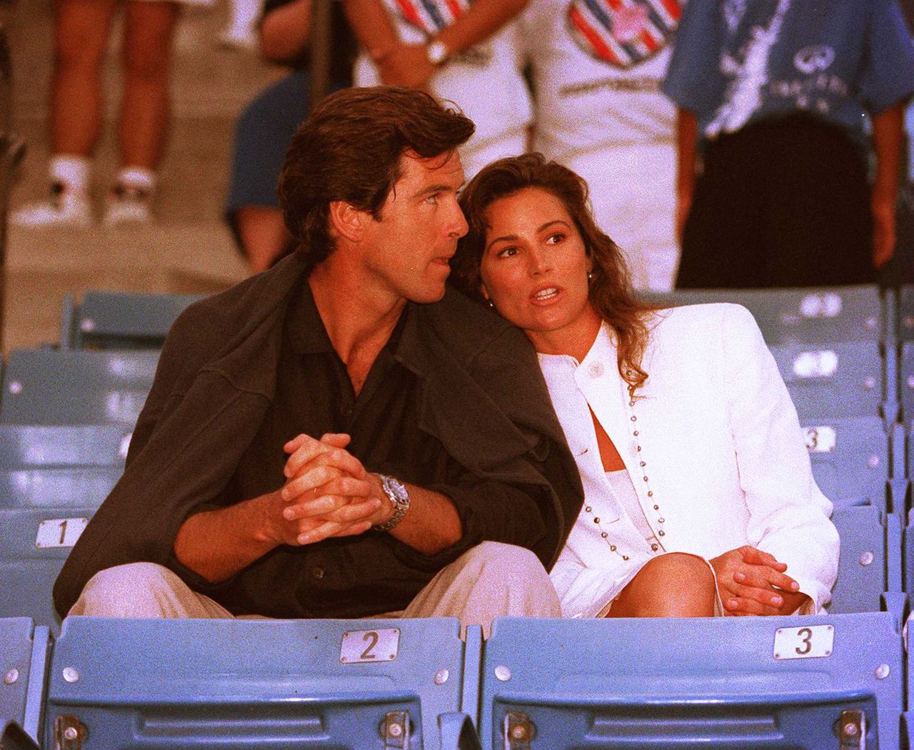 Pierce Brosnan and Keely Shaye Smith shared a close moment while watching the Infiniti Tennis Tournament in Westwood, California, on July 31, 1995. | Source: Getty Images.